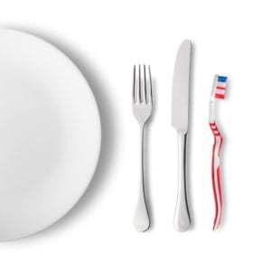 a new toothbrush on a table with a knife, fork, and plate